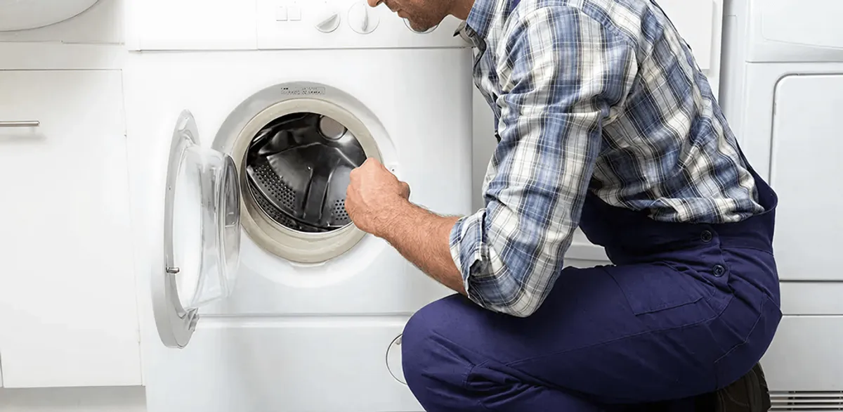 Handyman inspecting a dryer drum and internal parts for repair in New Orleans, LA