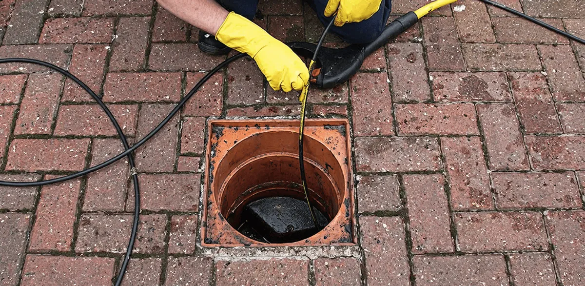 Drain cleaning technician using a drain snake to clear a clogged drain in New Orleans, LA