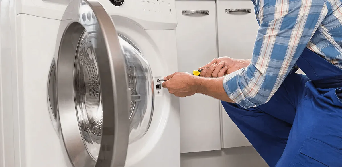 Handyman repairing a clothes dryer and checking electrical connections in New Orleans, LA